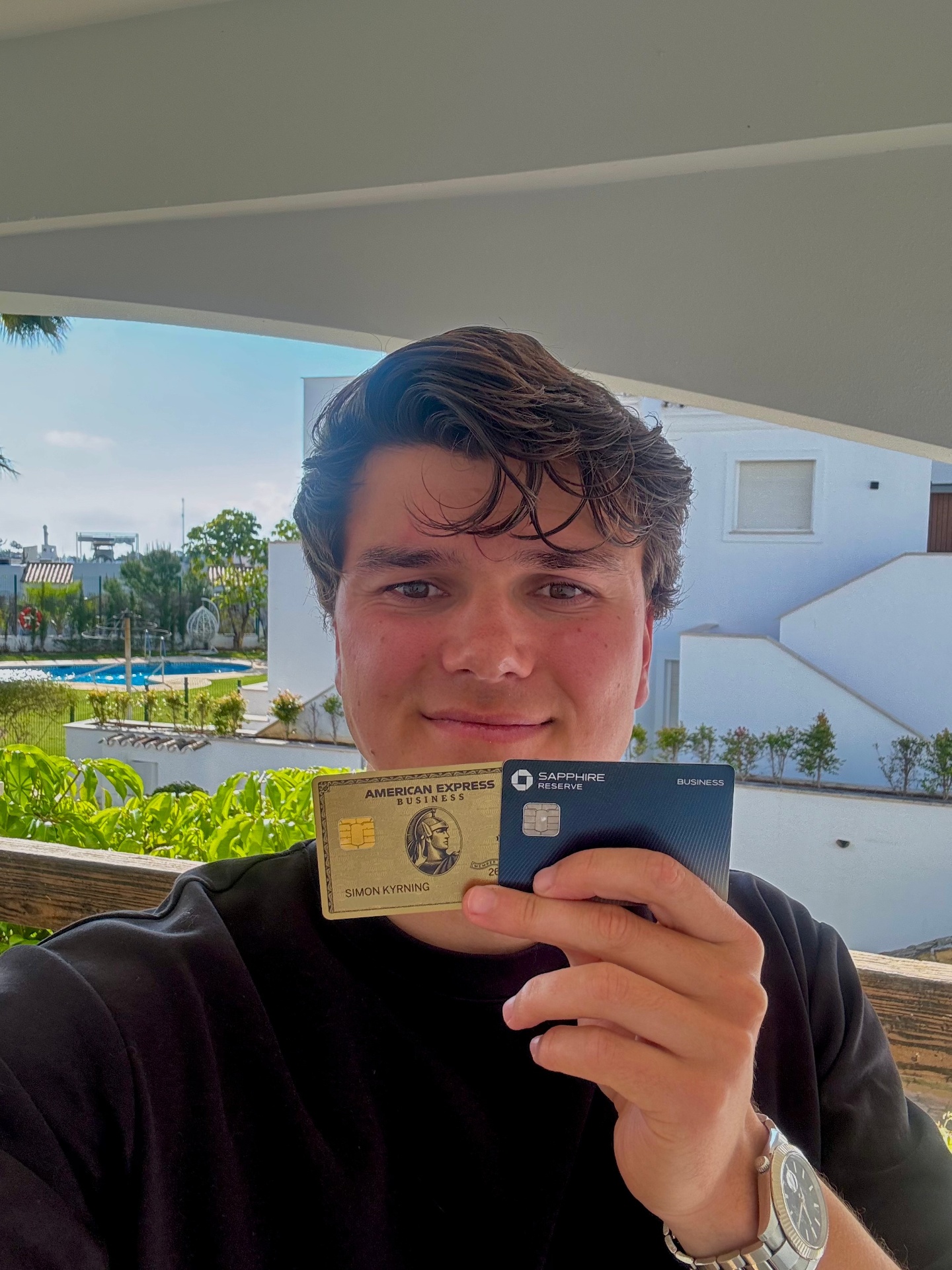 Smiling founder in clear weather holding gold Amex and blue Chase Sapphire cards